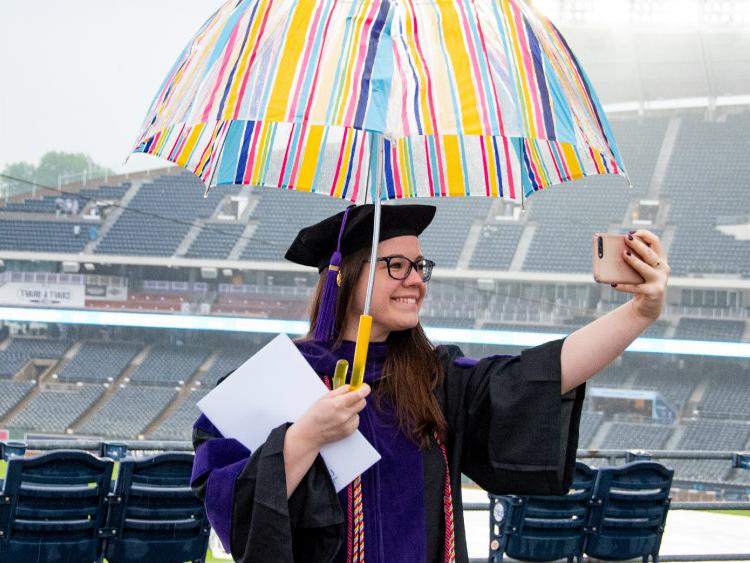以体育场为背景的女学生手持雨伞